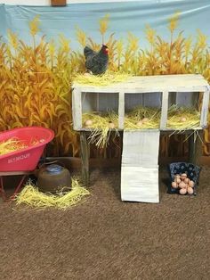 chickens are sitting on top of hay in front of a wall with corn stalks and a red wheelbarrow