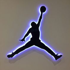 a basketball player jumping up into the air with a ball in his hand and lights behind him