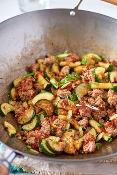 a pan filled with meat and zucchini on top of a table next to a knife