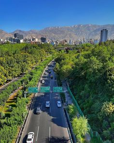 an aerial view of a city with mountains in the background and trees on both sides