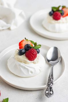 two small desserts with whipped cream and fruit on top are sitting on white plates