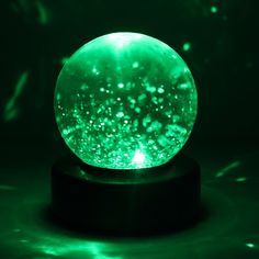 a glowing green ball sitting on top of a black stand