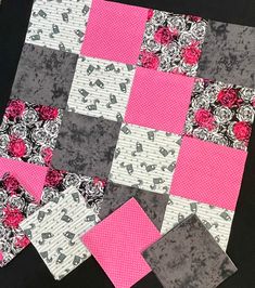 a patchwork quilt with pink and grey flowers on it, next to a piece of fabric