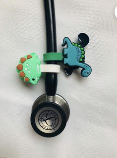 a stethoscope with two dinosaur charms attached to it's back end