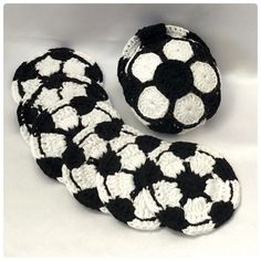 four black and white crocheted soccer balls