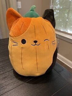 a stuffed cat sitting on top of a wooden table