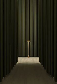 a cross in the middle of a room with green curtained walls and wooden floors