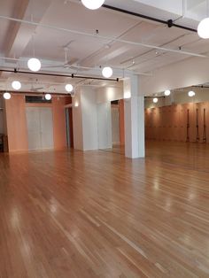 an empty room with hard wood floors and lights on either side of the wall or ceiling