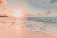 the sun is setting over an ocean with waves coming in to shore and sand on the beach