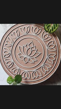 a round rug with a flower design on the floor next to a potted plant