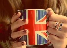 a woman holding a coffee cup with the british flag on it and two rings around her fingers