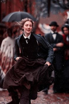 a woman is running in the rain with an umbrella over her head and other people behind her