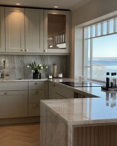 a kitchen with marble counter tops next to a large window overlooking the ocean and water