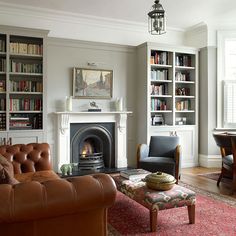 a living room filled with furniture and a fire place in front of a book shelf