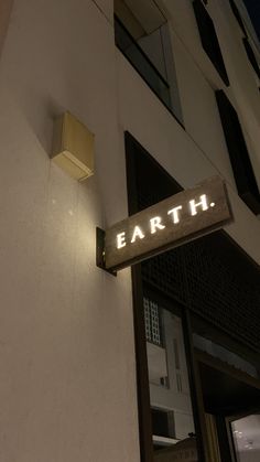 a sign that reads earth on the side of a building at night with lights above it