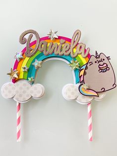 there is a cake topper with a hello kitty on it and a rainbow in the background