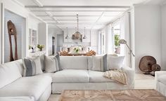 a living room filled with white furniture and lots of pillows on top of the couch