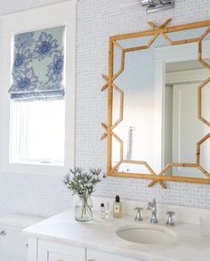 a bathroom with blue and white wallpaper, mirror, sink and toilet in it