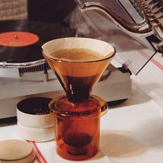 a glass pitcher filled with liquid sitting on top of a table next to record players