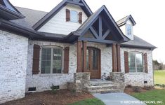 a white brick house with brown shutters on the front door and windows, along with stone steps leading up to it