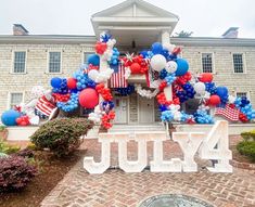 the fourth of july balloon arch is decorated with red, white and blue balloons in front of a brick building