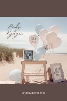 a baby announcement with balloons and an old tv on a table in the sand at the beach