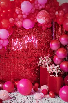 balloons and streamers fill the backdrop for a party with red, pink and white decor