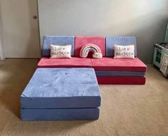 a blue and red couch sitting in front of a rainbow pillow on top of it