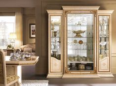 an elegant china cabinet with glass doors and gold trimmings in a living room