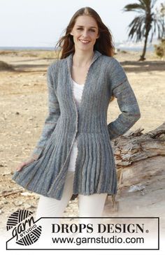 a woman standing in front of a tree wearing a cardigan sweater and white pants