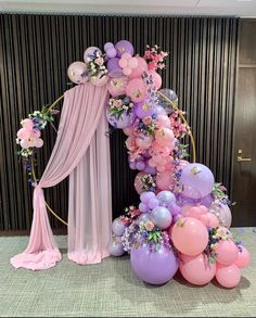 a balloon arch with balloons and flowers on it