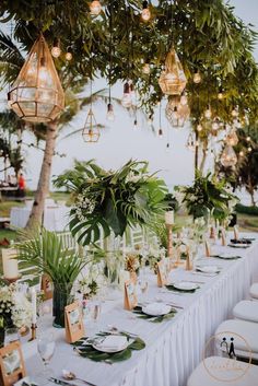 a table set up with place settings and greenery