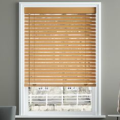 a window with wooden blinds on it and a white chair in front of the window