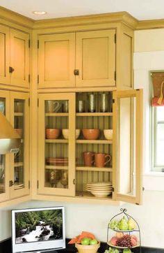 a kitchen with yellow cabinets and black counter tops, an apple bowl on the table in front of it