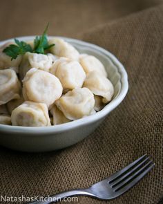 a white bowl filled with dumplings on top of a table