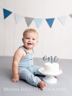 a baby sitting in front of a cake with the word one on it's top