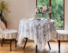 a table with two chairs and a white table cloth on it in front of a window