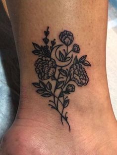 a black and white flower tattoo on the side of a woman's foot,