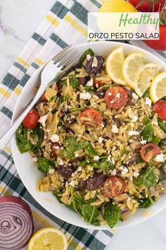 a salad with lemons, tomatoes, olives and feta cheese in a white bowl