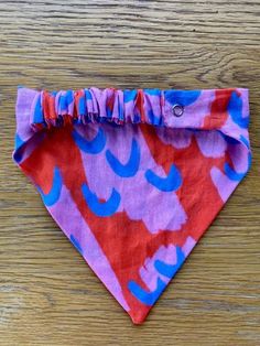 a pink and blue dog bandana sitting on top of a wooden table