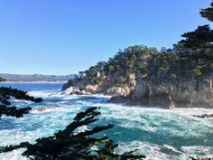 the ocean is blue and choppy with waves coming in from the rocks on the shore