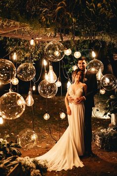 a bride and groom standing in front of bubbles hanging from the ceiling at night time