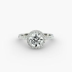 a round cut diamond ring with pave set shoulders and halos around the band