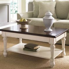 a coffee table with two vases on top of it in front of a couch