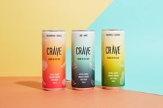 three cans of crave are sitting on a colorful surface, one is blue and the other is orange