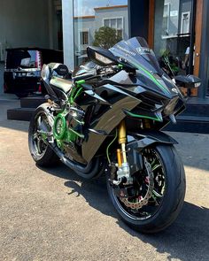 a black and green motorcycle parked in front of a building