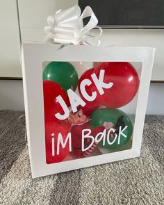 a white box with balloons in it that says jack i'm back on the front