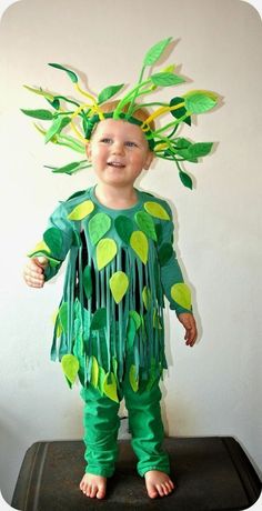 a young boy wearing a green costume with leaves on it's head and legs