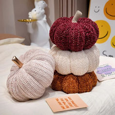 three knitted pumpkins are stacked on top of each other in front of a white teddy bear