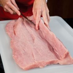 a person cutting meat with a knife on a cutting board